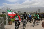رکاب‌زنی ملی‌ پوشان با پرچم ایران از روی پل طبیعت